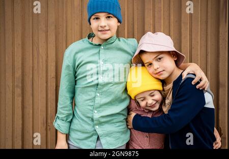 Bruder und Schwester stehen zusammen vor einer braunen Wand Stockfoto