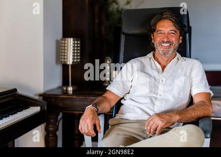 Lächelnder Mann auf Stuhl sitzend Stockfoto