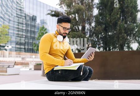 Lächelnder bärtiger Mann träumt, während er sich an die Wand lehnt Stockfoto