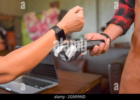 Kunden, die drahtlos oder kontaktlos mit der Smartwatch bezahlen. Store Worker akzeptieren Zahlungen über nfc-Technologie.geringe Schärfentiefe Stockfoto