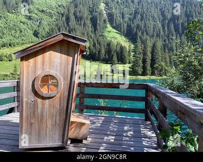 Die handgemachte Schaukelkabine mit spektakulärem Blick auf den smaragdgrünen See in Tirol Stockfoto