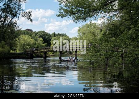 Sehen Sie die historische Nordbrücke mit Touristen überqueren und eine Familie von einem Boot unten angeln an einem sonnigen Tag mit einem blauen Himmel und weißen Wolken - Concord Stockfoto