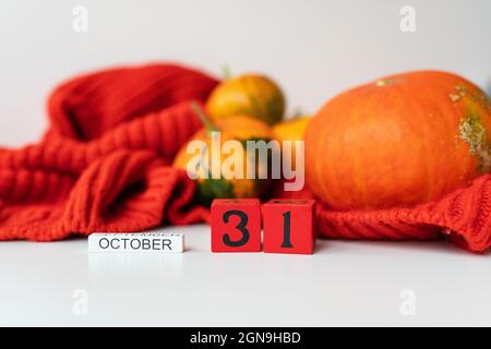 Holzwürfelkalender zeigt Halloween am 31. Oktober mit Kürbissen im Hintergrund. Feiertags- und Partykonzept Stockfoto
