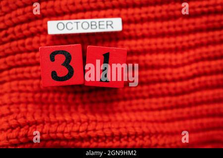 Holzwürfelkalender zeigt am 31. Oktober Halloween isoliert auf rotem Hintergrund rot gestrickter Pullover Stockfoto