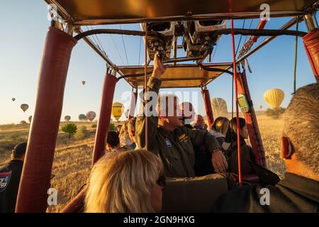 Kappadokien, Türkei - 14. September 2021: Ein Heißluftballonpilot navigiert seinen Ballon durch den Himmel in der Nähe von Goreme in der Region Kappadokien in der Türkei. Stockfoto