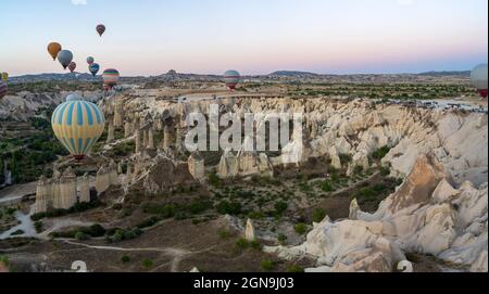 Heißluftballons fliegen über Berge Landschaft geologische Gesteinsbildung im Herbst während Sonnenaufgang in Kappadokien, Goreme Nationalpark, Türkei n Stockfoto