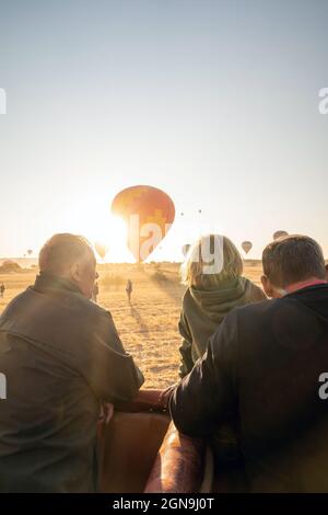 Kappadokien, Türkei - 14. September 2021: Eine Gruppe von Passagieren, die während des Sonnenaufgangs Heißluftballons betrachten Stockfoto