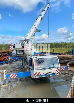 Ölindustrie. Sortierung von Bohrwerkzeugen, Rohren nach Durchmesser, Neuverlegung. Arbeiten mit einem Kran. Stockfoto