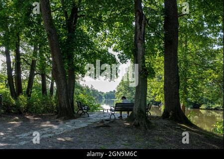 Unkenntliche Person entspannt sich an einem sonnigen Sommertag im Stadtpark am Motala-Fluss in Norrkoping. Stockfoto
