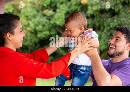 Eltern heben und spielen mit ihrem Baby in der Natur. Stockfoto