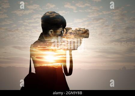 Doppelbelichtung des Menschen, der Fotos gemacht hat, und des Sonnenuntergangs. Stockfoto
