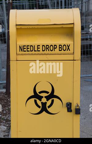 Gelbe Nadel-Drop-Box mit Gefahrensymbol und Schloss darauf. Stockfoto