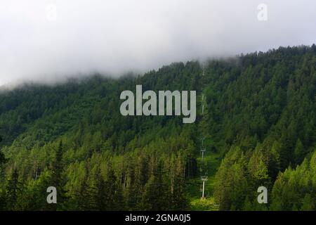 Leere Seilbahnen mitten im Wald mit Wolken, die herabfallen Stockfoto