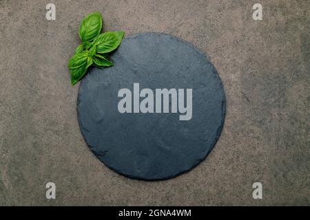 Leere Pizzaplatte für selbstgebackenes Backen auf dunklem Beton aufgesetzt. Food Rezept Konzept auf dunklen Stein Hintergrund Textur mit Kopierraum. Stockfoto