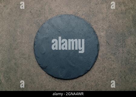 Leere Pizzaplatte für selbstgebackenes Backen auf dunklem Beton aufgesetzt. Food Rezept Konzept auf dunklen Stein Hintergrund Textur mit Kopierraum. Stockfoto