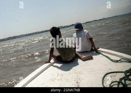 Zwei arme Kinder, die vor einem Fischerboot fahren Armut im Land der Dritten Welt Stockfoto