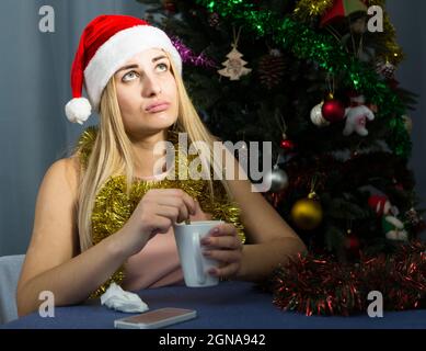 Mädchen ist gelangweilt und trinkt Tee in Silvester Nacht Stockfoto