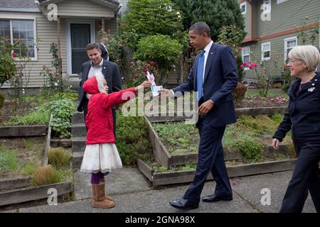 Präsident Barack Obama nimmt einen Brief und einen Strauß Papierblumen von Mieraye Redmond, 7, neben dem Haus entgegen, in dem er sich mit Nachbarschaftsfamilien in Seattle, Washington, traf., 21. Oktober 2010. (Offizielles Foto des Weißen Hauses von Pete Souza) Dieses offizielle Foto des Weißen Hauses wird nur zur Veröffentlichung durch Nachrichtenorganisationen und/oder zum persönlichen Druck durch die Betreffzeile(en) des Fotos zur Verfügung gestellt. Das Foto darf in keiner Weise manipuliert werden und darf nicht in kommerziellen oder politischen Materialien, Anzeigen, E-Mails, Produkten oder Werbeaktionen verwendet werden, die in irgendeiner Weise eine Genehmigung oder Zustimmung vorschlagen Stockfoto