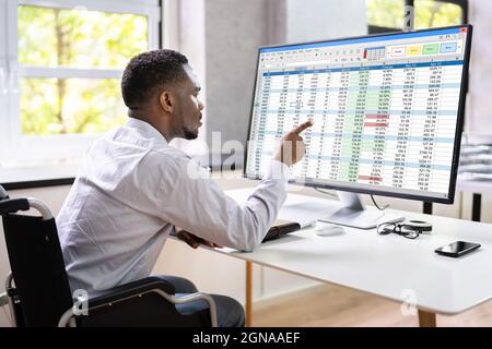 Medizinische Codierungstabelle auf dem PC. Afrikanischer Mann Im Rollstuhl Stockfoto