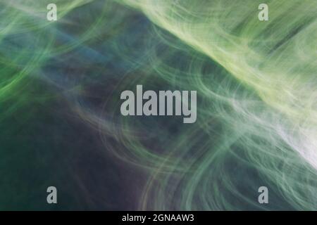 Zeichnen mit Licht, Darstellung von Strahlen, Kreisen, dünnen Linien, Blendung. Abstrakter Hintergrund in Grüntönen. Fotoeffekt. Stockfoto