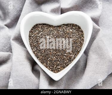 Chia Samen in weißer Schale auf grauem Textilhintergrund. Stockfoto
