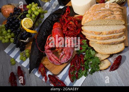 Geräucherter Stör, Hummer, Krebse, Brot, Käse und Früchte auf Holzoberfläche Stockfoto