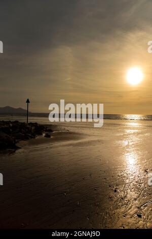 Dinas Dinlle Strand mit Ebbe- und Flut-Markierungen bei Sonnenuntergang. Konzept für einen Strandurlaub an der walisischen Küste Stockfoto