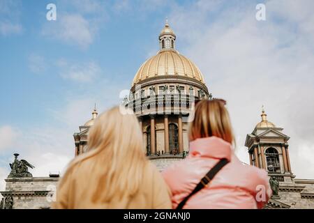 Isaakskathedrale in St. Petersburg. Verschwommener Vordergrund - zwei Touristenmädchen. Konzentrieren Sie sich auf die Kathedrale. Sightseeing- und Ausflugskonzept Stockfoto