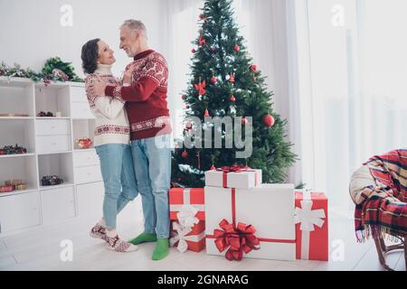 In voller Länge Foto von lustigen Paar alte Dame Mann Umarmung tragen Pullover Jeans Socken zu Hause Stockfoto