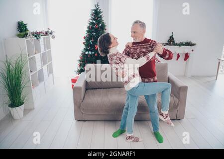 In voller Länge Foto von lustigen Paar alte Dame Mann Tanz tragen Pullover Jeans Socken zu Hause Stockfoto