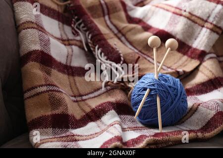 Garnknäuel mit Stricknadeln auf kariertem Kariert Stockfoto