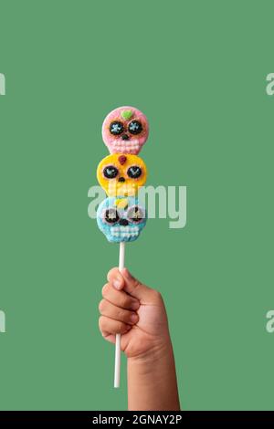 Kind Hand hält Süßigkeiten Schädel Lollipop auf grünem Hintergrund Stockfoto