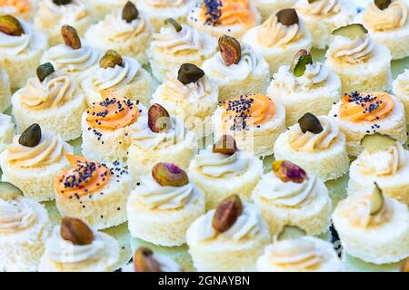 Kleine Häppchen mit Fischcreme, Pistazien und Mohn. Catering Fingerfood für Hochzeiten. Diagonale Komposition. Sandwiches auf Basis von Weißbrot. Gluten Stockfoto