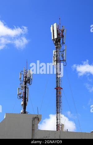 Antennenmast für drahtlose Kommunikation, Antennenmast für Mobiltelefone auf dem Dach eines baufälligen Gebäudes Stockfoto