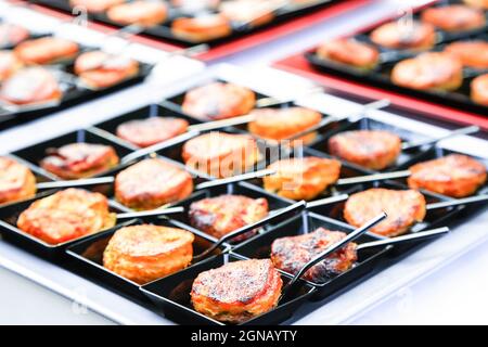 Set aus kleinen schwarzen quadratischen Gerichten mit Fingerfood. Backed orientalischen Snacks mit winzigen Löffeln. Catering-Layout. Gourmetküche. Menükonzept Stockfoto