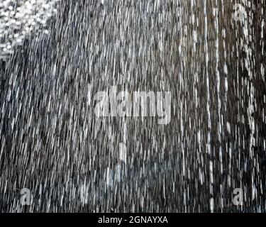 Abstraktes Bild von Wasser, das in Zeitlupe von einem Wasserfall sprüht. Schönes Bokeh, Stockfoto