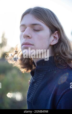 Weißer junger Mann aus europa mit langen blonden Haaren und geschlossenen Augen Stockfoto