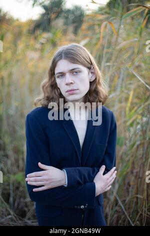 Weißer Mann mit langen Haaren in dunkler Kleidung in der Natur Stockfoto
