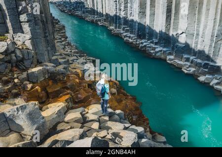 Wanderfrau mit Rucksack genießt den Studlagil Canyon. Einzigartige Jokulsa Basaltkolen und EIN Brufluss. Spektakuläre Outdoor-Szene von Island, Europa Stockfoto