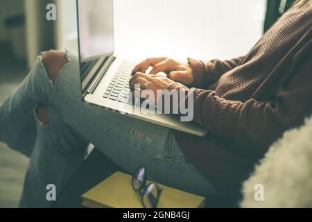 Junge Frau, die zu Hause am Laptop arbeitet. Nahaufnahme von weiblichen Händen, die auf der pc-Tastatur eines Teenagers tippen, mit einem technischen Gerät zum Lernen. Mädchen studiert online mit Co Stockfoto