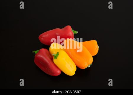 Rote, orange und gelbe Paprika, auf schwarzem Hintergrund Komposition Stockfoto