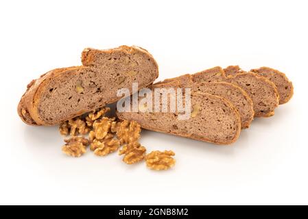 In Scheiben geschnittenes Buchweizenbrot, das mit Walnüssen auf weißem Hintergrund mit verstreuten Walnüssen in Schale geknetet wurde Stockfoto