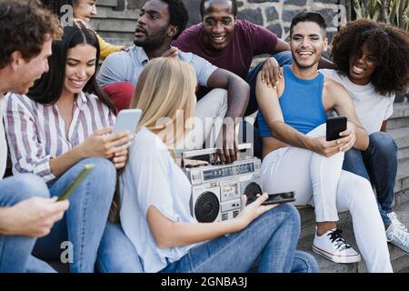 Junge, vielfältige Menschen tanzen und hören Musik mit Boombox-Stereo im Freien in der Stadt - Schwerpunkt auf Transgender-Mann-Gesicht Stockfoto