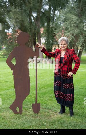 Beelitz, Deutschland. September 2021. Die Popsängerin Dagmar Frederic steht bei der Pressekonferenz zur Präsentation des Geländes der State Garden Show 2022 im Park neben der Figur eines Gärtners. Kurz zuvor wurde der Künstler vom Bürgermeister der Stadt zum 'musikalischen Botschafter' der Laga ernannt. Quelle: Soeren Stache/dpa-Zentralbild/dpa/Alamy Live News Stockfoto