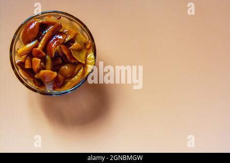 Eingelegte Waldpilze in einer Glassäge auf orangefarbenem Hintergrund. Hochwertige Fotos Stockfoto