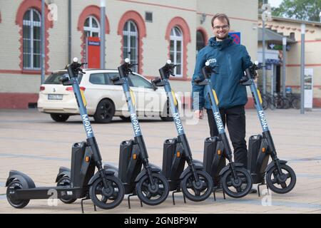 24. September 2021, Mecklenburg-Vorpommern, Greifswald: Adrian Merker von der Firma mir Solutions GmbH, richtet die Elektroroller vor dem Bahnhof ein.der Rostocker Anbieter mir Solutions GmbH startet am selben Tag mit einem Angebot von 100 E-Scootern, die in der ganzen Stadt verteilt sind.für Greifswald, Die Stadt hat ein maximales Kontingent von 300 E-Scootern zugelassen.gäbe es in Zukunft mehrere Anbieter, würde die Anzahl pro Anbieter entsprechend reduziert werden.für die Altstadt war die maximale Anzahl an E-Scootern auf 100 begrenzt.Es ist ein sogenanntes Free-Floating-Angebot - Sie Stockfoto