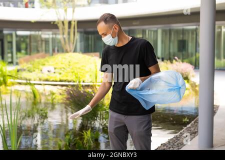 Mann, der im Park Hausmüll aus Plastik abholt Stockfoto