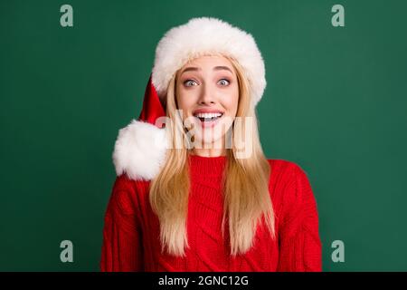 Foto-Portrait blonde Frau in santa Hut lächelnd erstaunt isoliert grünen Hintergrund Stockfoto