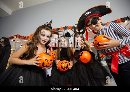 Kinder, die als verschiedene gruselige Charaktere verkleidet sind, wollen auf der Halloween-Party Tricks oder Leckereien. Stockfoto
