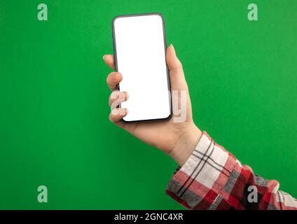 Frau Hand hält Handy-Mockup-Bildschirm auf einem grünen Hintergrund, Platz kopieren Stockfoto